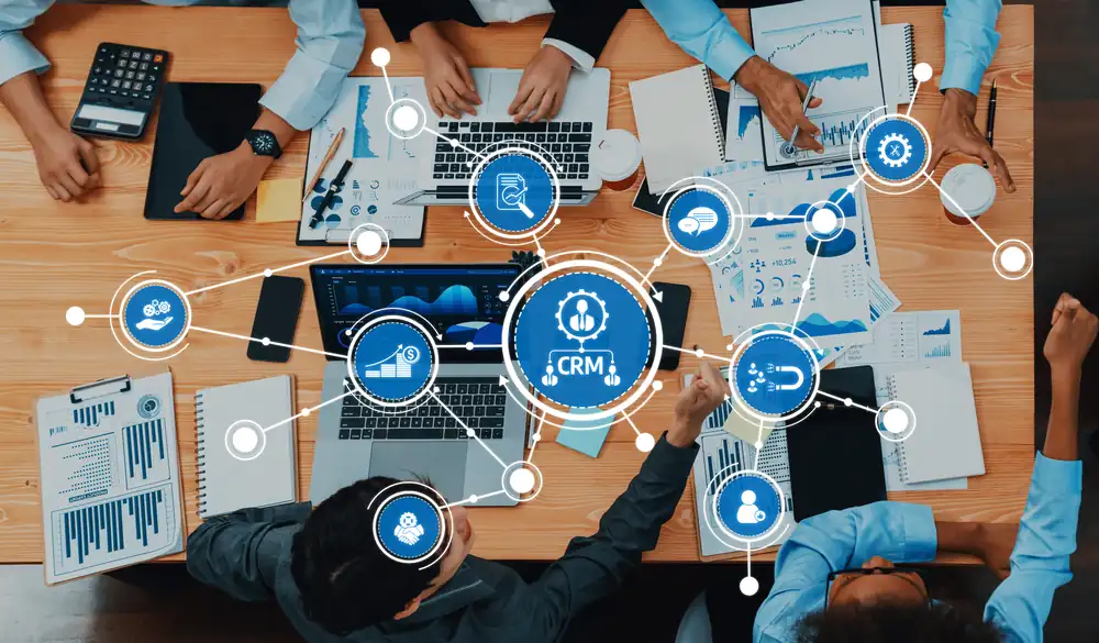 Team at a table with laptops, connected by a CRM network of customer processes